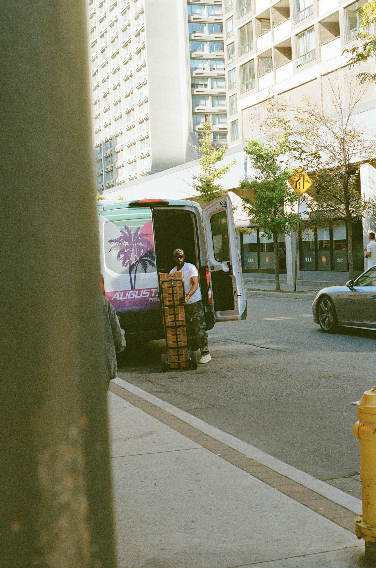 Delivery driver unloading boxes from a white delivery van with a hand truck